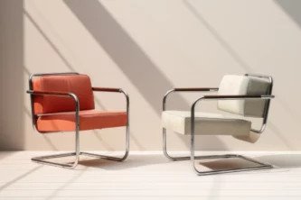 Ghế bành Bauhaus với khung thép không gỉ, tay vịn gỗ và bọc da màu đỏ trắng, thể hiện tinh thần thiết kế tối giản.